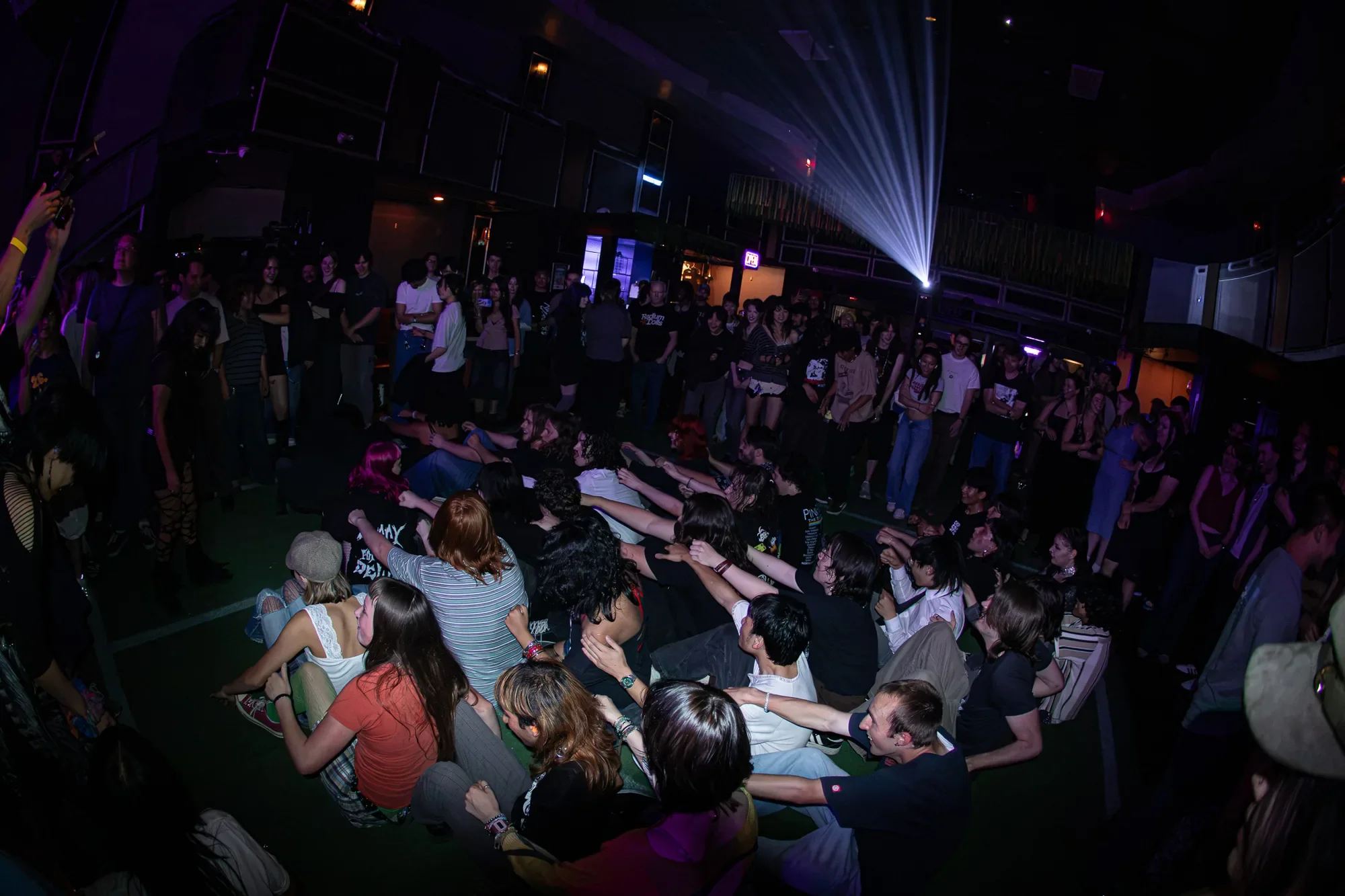 a crowd of people sitting on the floor of the venue pretending to row a viking ship