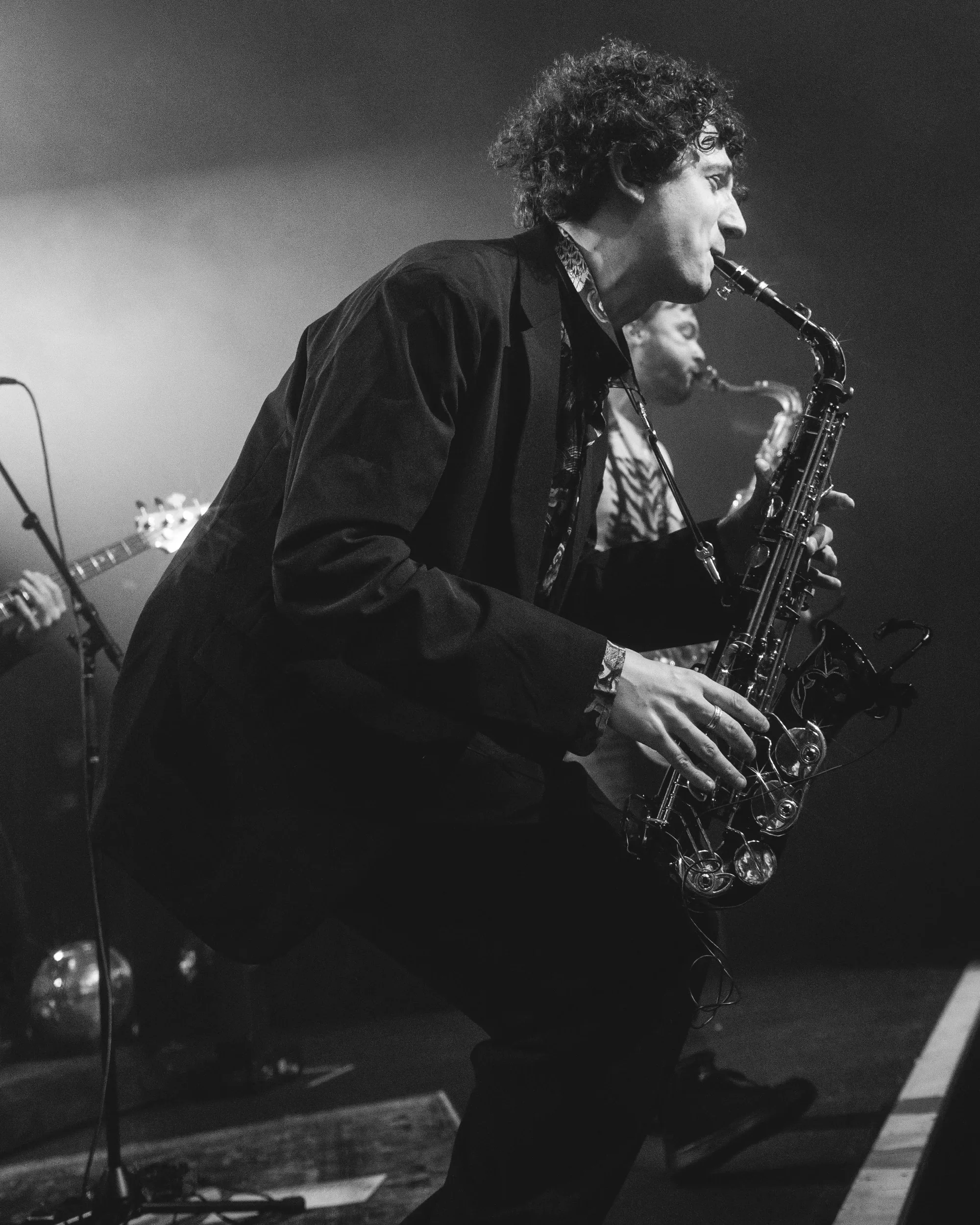 A saxophonist leaning into a solo in a black-and-white concert photograph.
